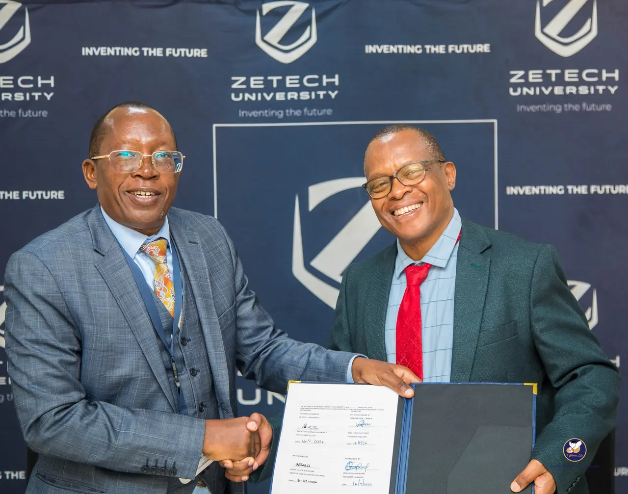 Eng. Mike Mutungi and Prof. Njenga Munene shake hands while holding the signed memorandum of understanding between I Choose Life – Africa and Zetech University.